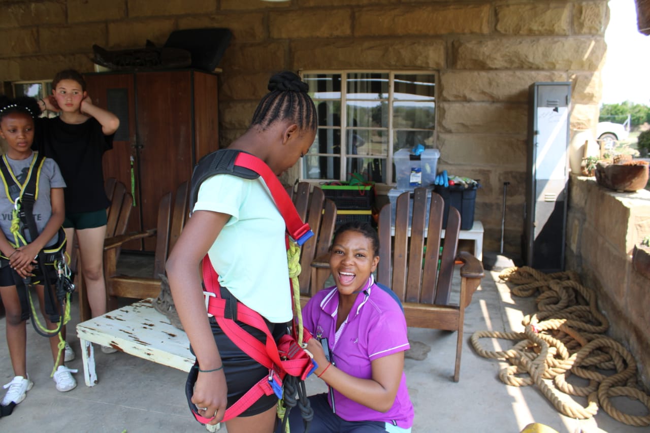 A facilitator fitting a learner with a safety harness at On-Track Adventure